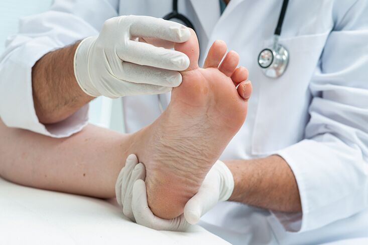 a dermatologist examines a patient’s feet